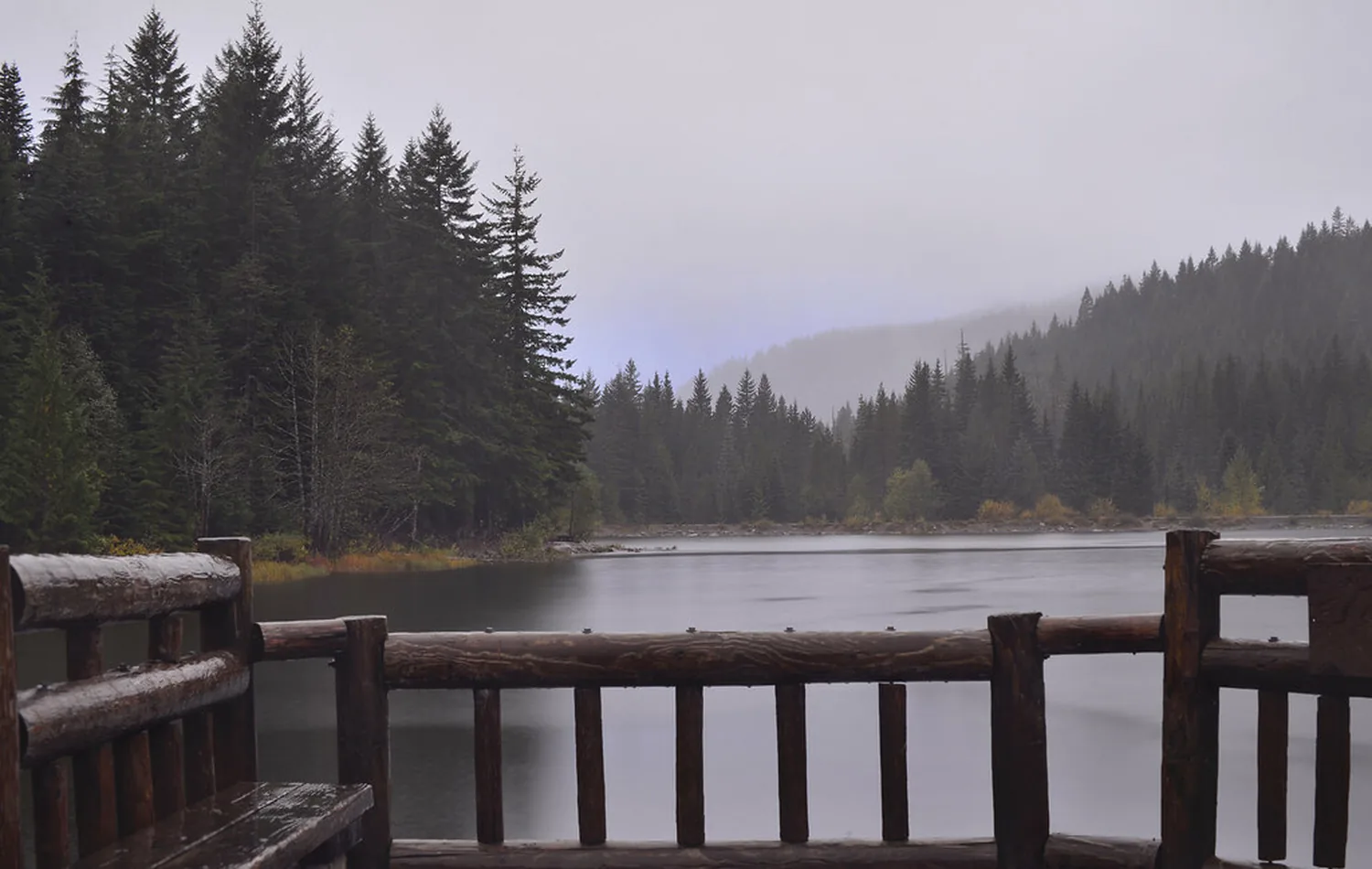 Heavy timber railing looking out over a lake and treeline