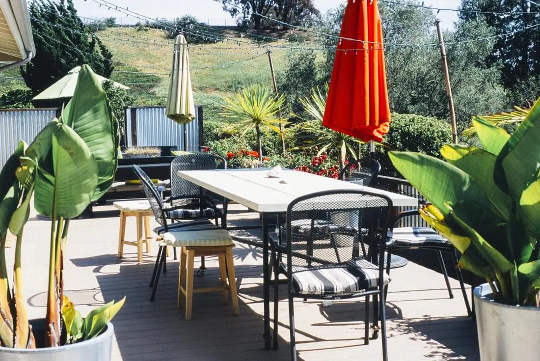 Outdoor dining set and folded umbrellas on a raised terrace