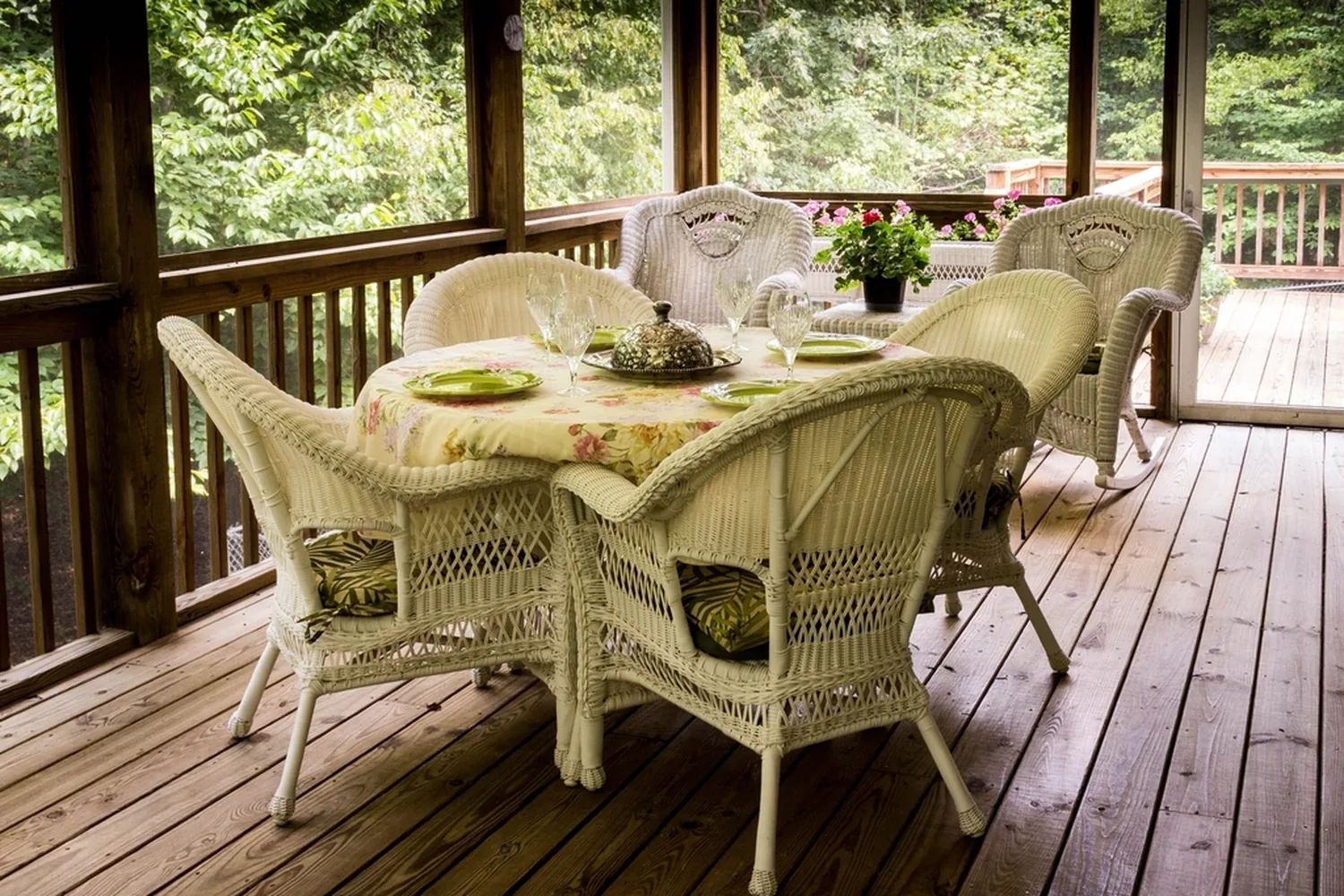 Wicker table and chairs on a covered porch with a stained wood floor